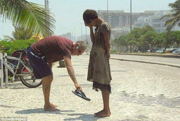 Một người đàn ông nhường lại đôi dép đang mang cho cô bé vô gia cư trên đường phố Rio de Janeiro.