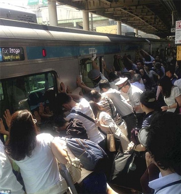 Những hành khách đang cố gắng đẩy thành tàu điện khi có một người không may mắc kẹt giữa thành tàu và sân nhà ga.