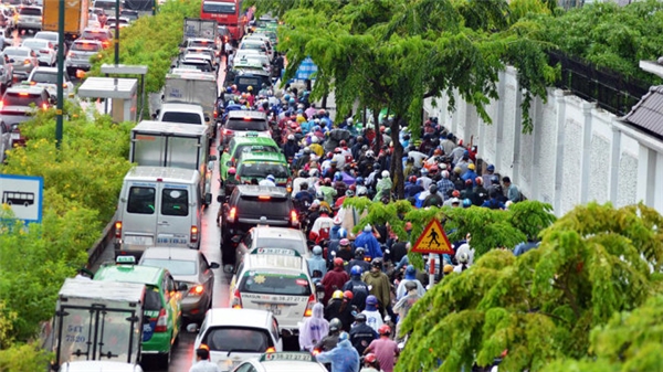 Nhiều người đội mưa kẹt xe ở đường Phạm Văn Đồng. (Ảnh: Lê Phan)