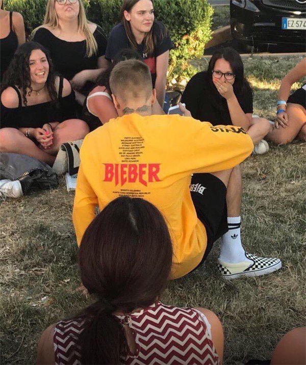 Justin Bieber ngồi trên cỏ trò chuyện cùng fan trước khi lên máy bay.