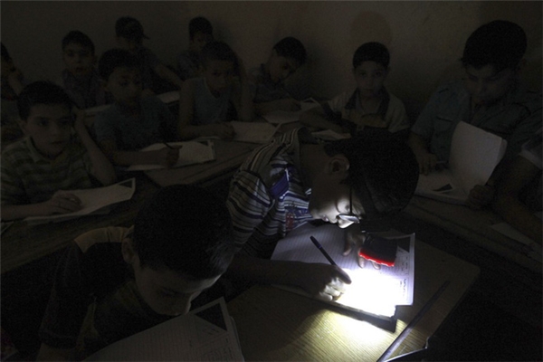 Phòng thi cúp điện, một cậu học sinh may mắn có được chiếc đen pin chiếu sáng tại một trường học tại một trường học ở quận Aleppo's al-Sha'ar. (Ảnh: Internet)