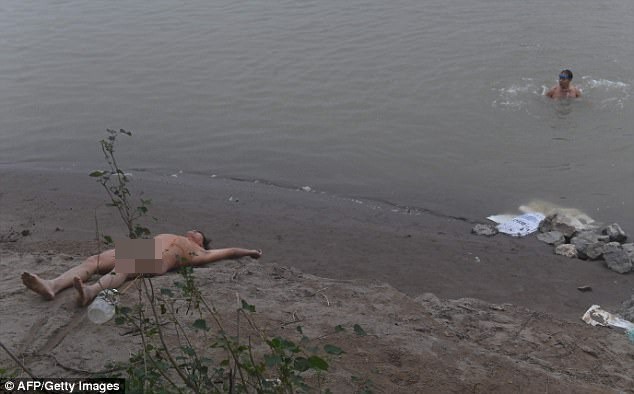 
Người đàn ông nằm "phơi mình" trên bờ sông đầy khoan khoái.