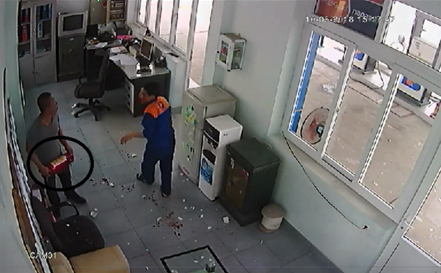 
Đối tượng cầm bình cứu hỏa đe dọa nhân viên bán xăng sau khi đánh người này chảy máu. (Ảnh cắt từ clip)