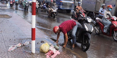 Người đàn ông, cậu bé nhặt rác thông cống khi trời mưa
