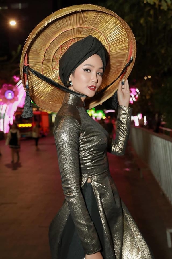 
Hoa hậu H'Hen Niê nổi bật trong tà áo dài ánh vàng cùng chiếc nón quai thao quen thuộc của dân tộc Việt Nam.