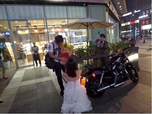  
Cô gái quỳ xuống cầu hôn bạn trai trước trung tâm thương mại. (Ảnh: Sina)