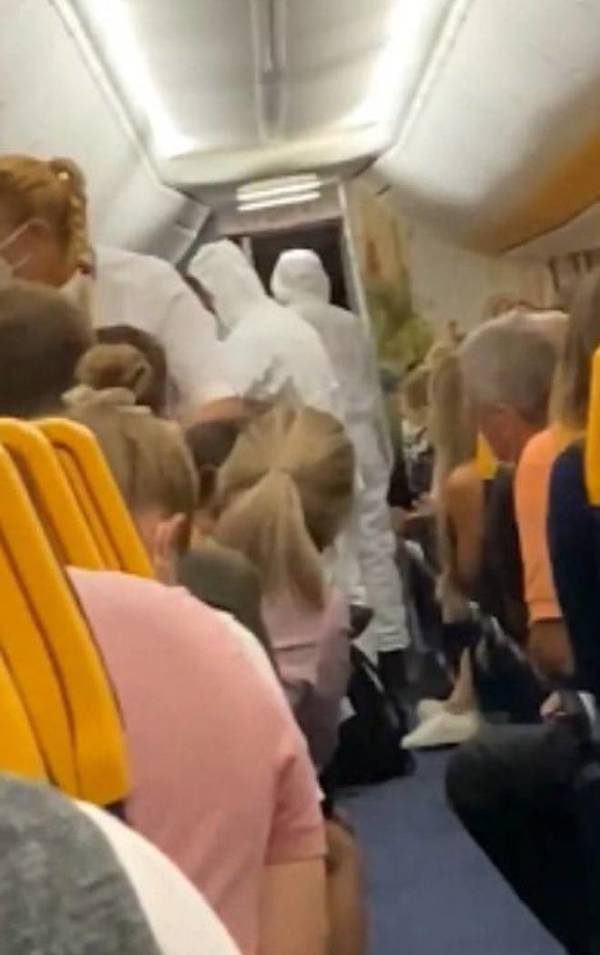  
Hình ảnh nhân viên mặc đồ bảo hộ đưa hai hành khách xuống khỏi chuyến bay. (Ảnh: Cắt từ clip)