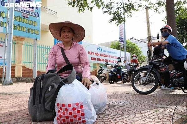 Chị Hóa tay xách nách mang đợi con trước cổng điểm thi Trường THPT Chu Văn An (TP Buôn Ma Thuột).