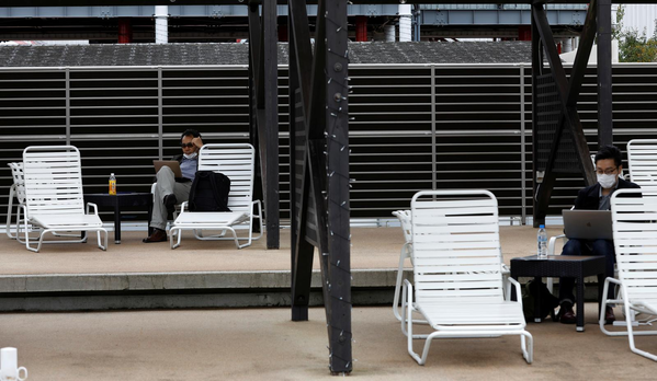 
Mọi người ngồi làm việc trên những chiếc ghế tại hồ bơi - Ảnh Reuters