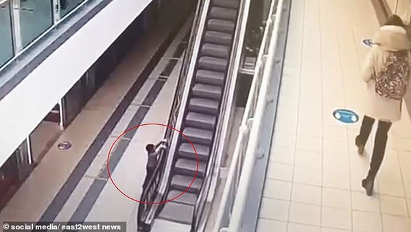 Một cậu bé bốn tuổi bám vào thành thang cuốn tại trung tâm mua sắm Global City ở Moscow, Nga, sau khi nắm lấy tay vịn khi chơi đùa