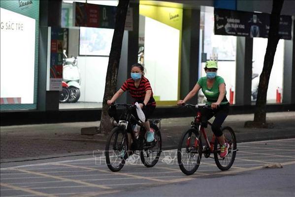  
Hai người đạp xe lúc rạng sáng 26/7 trên đường Lê Duẩn. (Ảnh: TTXVN)