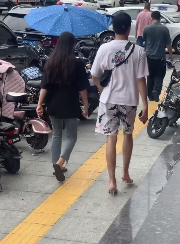 Chàng trai sẵn sàng đổi dép của mình cho bạn gái khi nhìn thấy cô đi giày cao gót đau chân. (Ảnh: Weibo)