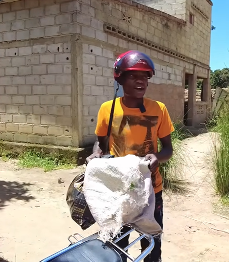  Lindo đặt thùng kem lên xe máy, đi vào bản để tặng cho các em nhỏ. (Ảnh: YouTube Lindo Vlogs - Cuộc sống ở châu Phi)