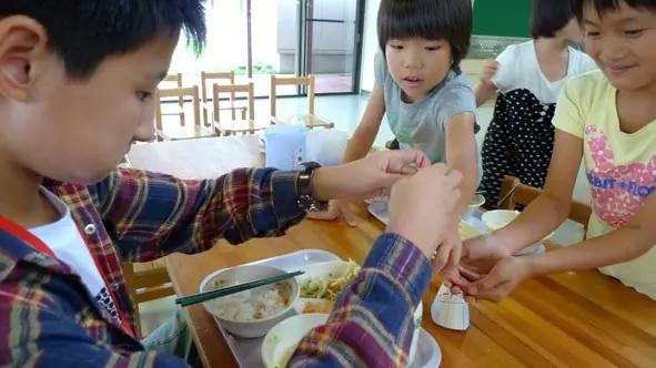 
Học sinh của đoàn Trung Quốc vừa mở xong chai sữa thì sẽ có học sinh Nhật tới thu dây buộc và vỏ nilon lại. (Ảnh: Internet)