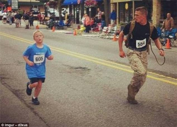 
Một người lính hải quân chạy chậm lại để cổ vũ tinh thần và giúp cậu bé hoàn tất đường đua của mình.