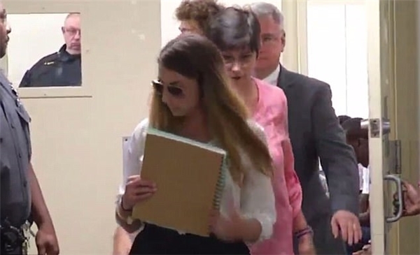 Cô giáo trẻ đã dùng quyển sổ để che mặt khi xuất hiện tại tòa.