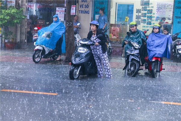 
Người phụ nữ không kịp mặc áo mưa nên phải chịu cảnh ướt sũng cả người. (Ảnh: Anh Thư)