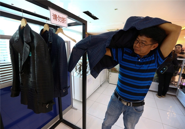 
Một du khách người Trung Quốc đang mặc thử một chiếc áo làm từ da cá sấu.
