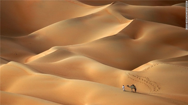 
Sa mạc Haneem, Các tiểu vương quốc Ả Rập: Một người đàn ông đang dẫn con lạc đà của ông ta đi qua sa mạc Haneeem - nằm cách Abu Dhabi khoảng 170 cây số về phía tây.