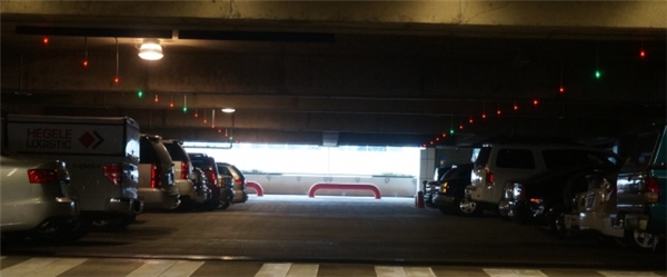 Một gara đậu xe với đèn xanh lá cây phát sáng từ phía xa để đánh dấu chỗ trống.