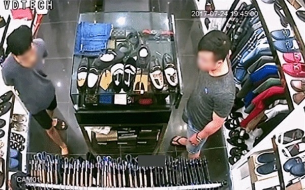 
Nam thanh niên được cho là đã ăn trộm chiếc ví (bên phải) giả vờ hỏi han các mẫu khác nhằm thu hút sự chú ý của nhân viên bán hàng .