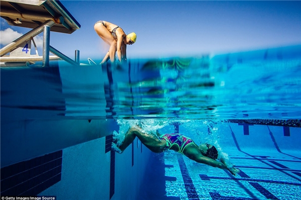 
Một người phụ nữ đang bơi trong bể bơi ở Miami (Florida, Mỹ) trong khi người bạn phía trên đang chuẩn bị nhảy xuống bể. Ảnh: Getty Images/Image Source.