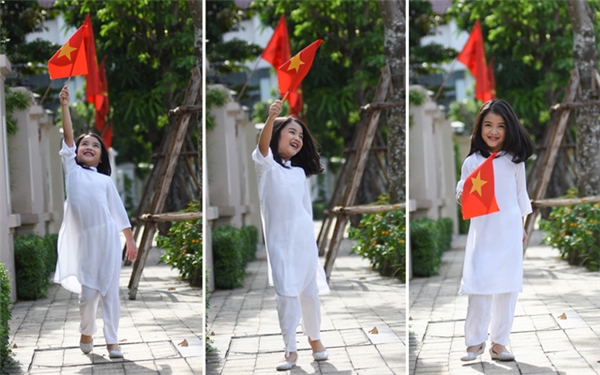 
Bảo Hân diện áo dài trắng, nở nụ cười hồn nhiên khi ngắm những lá cờ đỏ sao vàng tung bay trên phố.