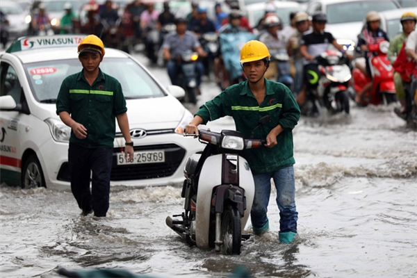 
Công nhân vất vả đẩy xe chết máy do ngập nước trên đường Nguyễn Hữu Cảnh - Ảnh: HỮU KHOA
