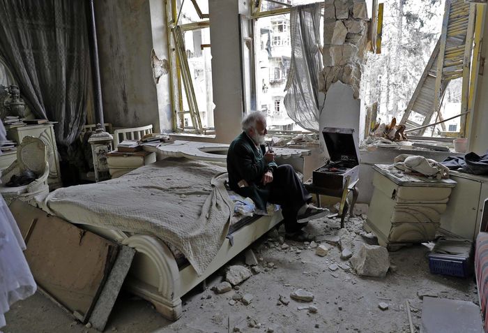 
Mohammad Anis, 70 tuổi, đang bình thản ngồi hút tẩu và nghe nhạc trong căn phòng đổ nát của ông tại thành phố Aleppo, Syria. Chiến tranh đã cướp đi của ông tất cả.