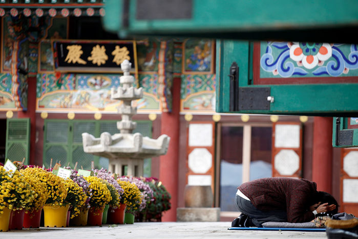 
Người phụ nữ này đã quỳ sạp hàng giờ trước cửa đền để cầu khấn cho con của mình