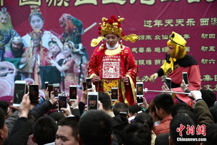 
Người dân xếp hàng giơ smartphone lên để quét mã QR trên người Thần Tài tại tỉnh Hà Nam, Trung Quốc