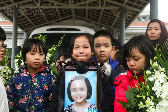 Bạn bè và người thân cầm di ảnh của bé Hải An trong ngày tổ chức tang lễ. Ảnh: Lao Động