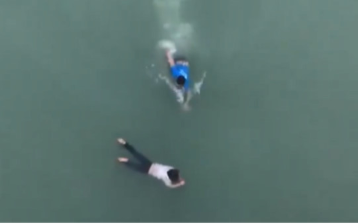 
Khoảnh khắc anh Huân cứu cô gái đang vùng vẫy trong dòng nước. Ảnh cắt từ clip.