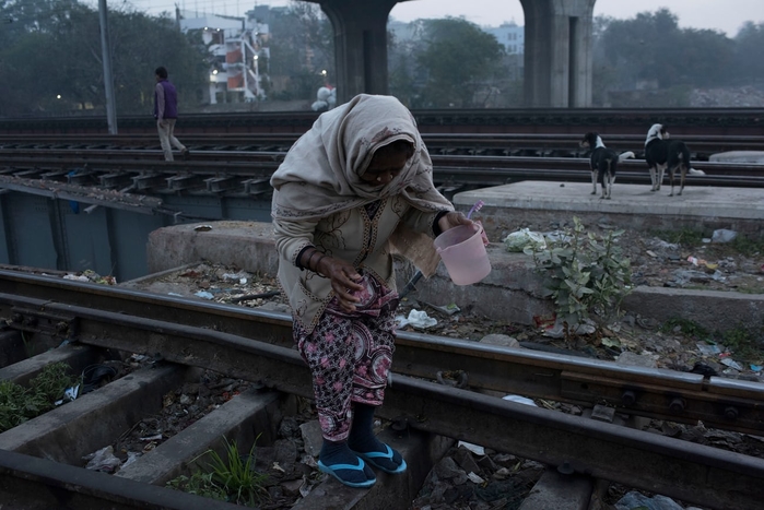 Một phụ nữ tìm chỗ để đi vệ sinh trên đường ray tàu hỏa vào sáng sớm tại khu ổ chuột Anna Nagar ở Delhi, Ấn Độ (Ảnh: Andrea Bruce)
