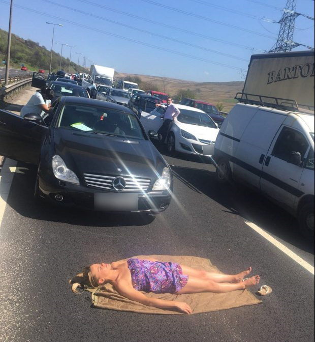 
Không muốn ngồi trong xe ngột ngạt nên cô gái trẻ đã đem chăn ra nằm để phơi nắng giữa đường