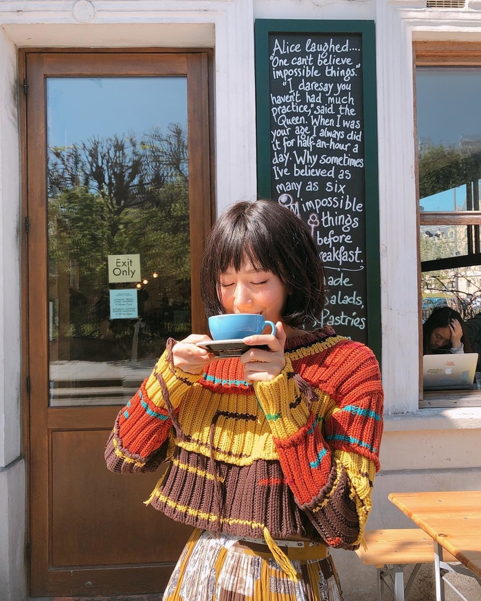 
Hình ảnh Min đang nhâm nhi tách coffee buổi sáng trong chiếc áo đan len nhiều gam màu tương phản độc đáo.