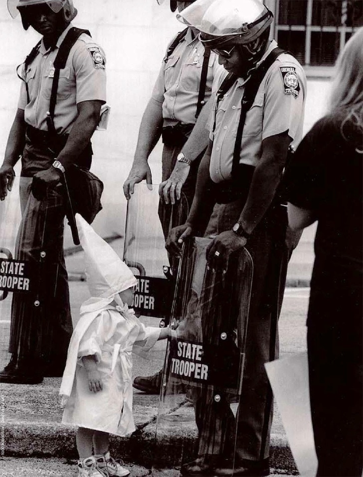 Em bé da trắng thuộc Đảng KKK (một hội kín lớn ở Mỹ đề cao tư tưởng Người da trắng thượng đẳng) đang chơi với tấm khiên của người cảnh sát tuần tra Mỹ gốc Phi trong một cuộc diễu hành Klan ở Georgia vào năm 1922.