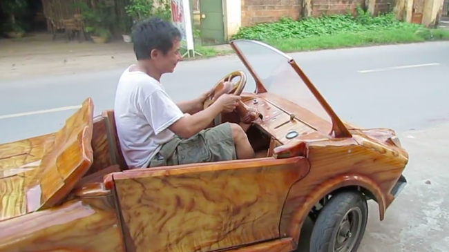 
Người đàn ông điều khiển chiếc xe ô tô bằng gỗ - Ảnh: Khuat Dien