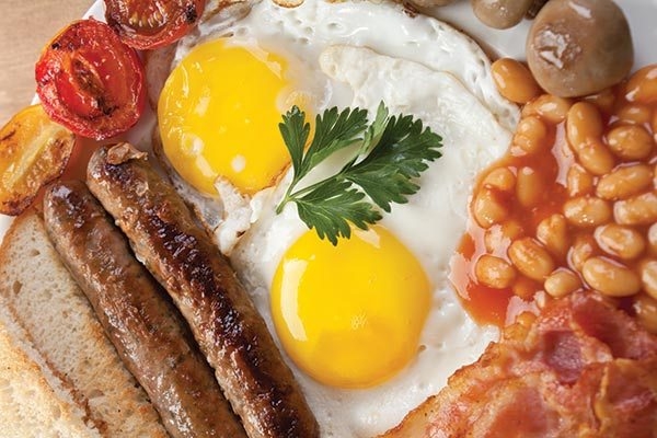 ​Bữa ăn dinh dưỡng của người Anh bao gồm trứng, xúc xích, thịt xông khói và cà chua nướng đảm bảo nguồn năng lượng dồi dào cho ngày làm việc.
