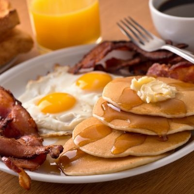 ​Một bữa sáng kiểu Mỹ điển hình với bánh pancakes, trứng và thịt xông khói.