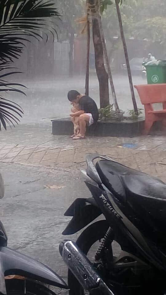 
Giữa cơn mưa tầm tã, một cậu nhóc đang ôm chặt để che chở cho người bạn cún nhỏ bé của mình​ - Ảnh: Internet