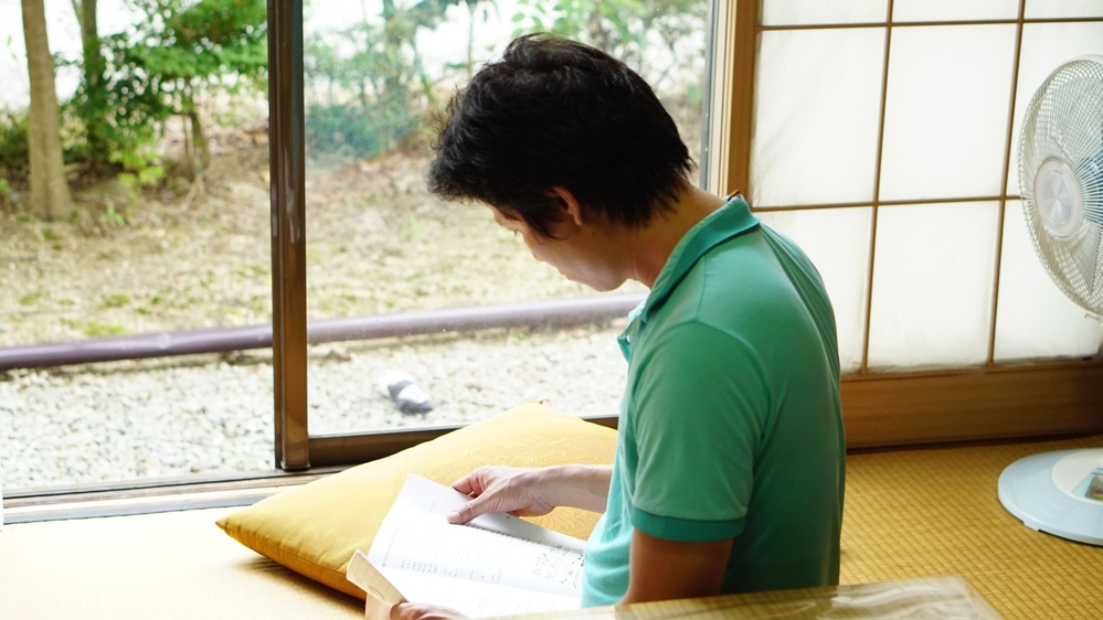 
C. ngồi đọc sách tại nhà tạm trú do anh Okabe mở