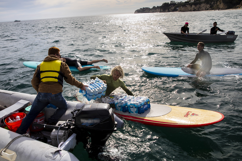 
Vì bị cảnh sát chặn lại nên họ quyết định vận chuyển đồ tiếp tế bằng ván lướt sóng để đưa vào bờ.