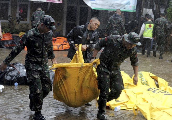 Binh sĩ khiêng thi thể nạn nhân sóng thần tại Carita, Indonesia, hôm 23/12. Ảnh: AP.