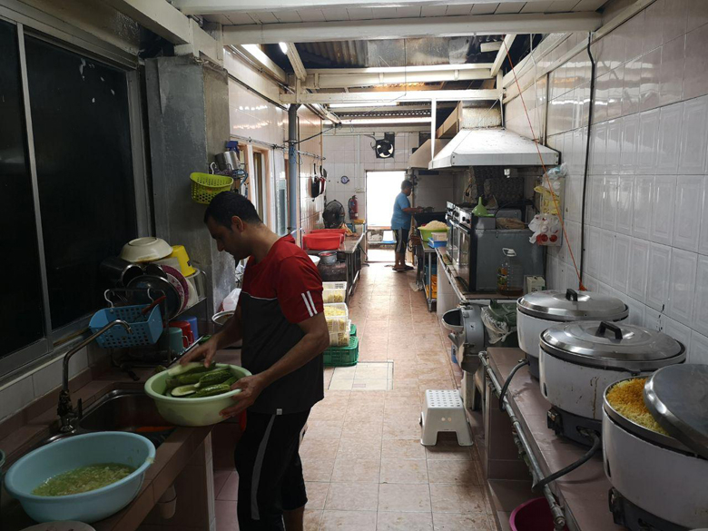 
Hai người đầu bếp đứng nấu trong căn bếp chật chội của FFFA.