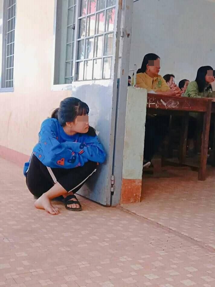 
Hình ảnh nữ sinh ngồi bệt dưới đất, ngóng vào trong lớp đang họp phụ huynh để xem giáo viên... - Ảnh: Internet