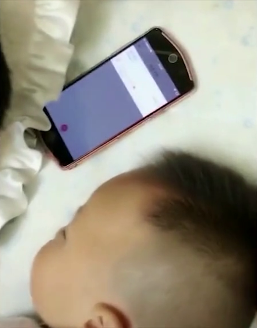 
Ông bố bật một bài hát trên điện thoại để ru con ngủ, còn mình thì tranh thủ ngủ trước.