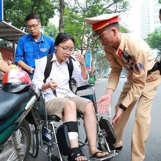  
Chiến sĩ cảnh sát giao thông giúp thí sinh nữ bị thương ở chân di chuyển cùng với thanh niên tình nguyện