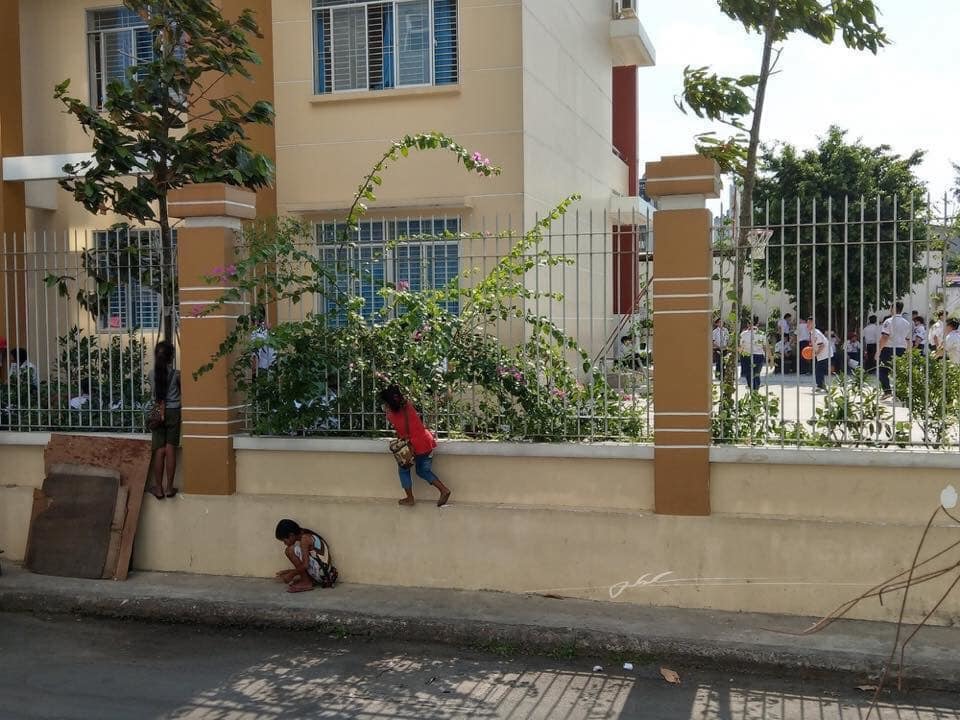  
Hình ảnh ba em bé bám vào vách tường của một ngôi trường