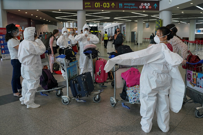  
Nhiều hành khách mặc đồ bảo hộ tại sân bay (Ảnh: Reuters)